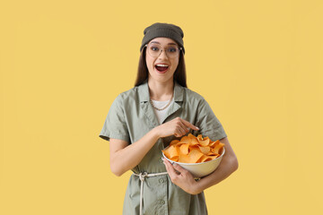 Sticker - Young woman with bowl of potato chips on yellow background