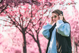 Fototapeta Miasto - woman portrait in sunglasses with headphones blooming sakura on background