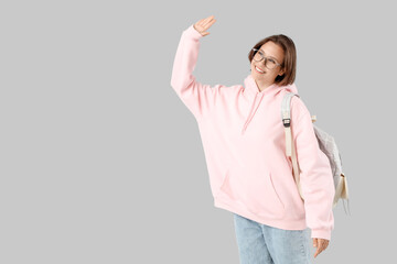 Sticker - Happy female student with backpack waving hand on white background