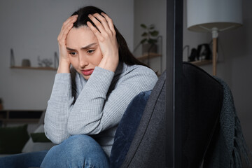 Wall Mural - Depressed young woman sitting in armchair at home