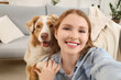 © Pixel-Shot - Young woman with cute Australian Shepherd dog taking selfie at home