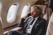Handsome middle aged businessman in suit talking on mobile phone sitting in plane during business trip