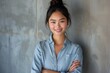 © Twinny B Studio - Confident and elegant businesswoman in blue, long hair styled in bun, cheerful expression, textured office backdrop