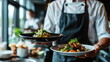 © seogi - Close-up of two plates of food placed on both hands of the chef in the hotel kitchen.