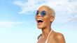 Happy young laughing woman at the beach side, wearing sunglasses, portrait of African latin American woman in sunny summer day with blue sky, concept of a seaside summer beach holiday