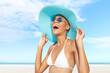 Happy young woman at the beach side, wearing a turquoise sun hat, blue sunglasses and bikini, portrait of African latin American woman in sunny summer day with blue sky, concept of a summer holiday