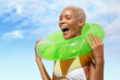 Happy laughing fun young woman holding green swim ring, African latin American woman in sunny summer day with blue sky. Concept of a seaside vacation, shopping for a summer beach holiday or travel