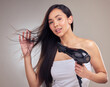 © peopleimages.com - Asian woman, hairdryer and confident with portrait in studio for growth, straighten and chemical treatment on gray background. Female person, proud and smile with clean hair, keratin and hairstyle