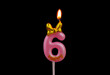 Burning pink birthday candle with golden bow isolated on black background, number 6.	