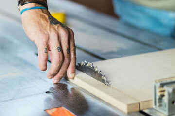 The joiner saws a piece of wood in 2 parts on with electric tool