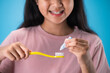 Close up of girl hands hold toothbrush and toothpaste isolate on blue background.