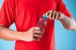 Close-up of man hand holding water bottle isolate on blue background.