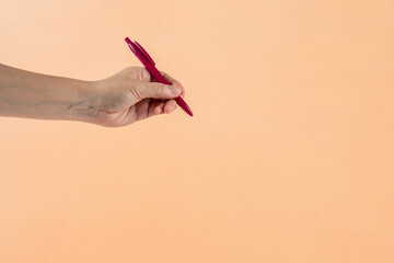 Wall Mural - Red plastic pen in hand. Isolated on cream background