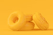 Stack of glazed donut with sprinkles on plain monochrome yellow color