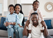 © peopleimages.com - Home, portrait and black family in lounge, smile and happiness with weekend break, cheerful and love. Face, parents or mother with father, children and kids with support, care or trust in living room