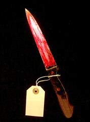 Bloody knife with yellow label on black background