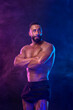 Athlete bodybuilder in neon colors. Fit man posing on black background. Sports concept. Bodybuilding competition. Download, high resolution, photo.