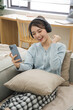 © Q88 - Portrait of Asian woman sitting on sofa at home