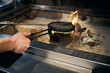 Cropped male chef hand frying pancake in pancake maker in burning fire place