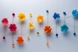 Colorful paper flowers arranged in row on white surface