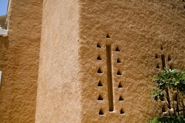 Low angle view on ancient clay walls of arabic tower in heritage village under clear sky