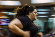Overweight woman runs on treadmill in gym, motion blur effect