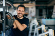 A positive man smiling for the camera, resting from his workout, at the gym.