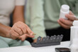 Senior woman hands taking a pill from weekly organizer. Health care, medicine and treatment concept