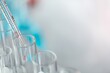 © BESTIMAGE - A close up of a pipette adding a red liquid to a test tube in a laboratory with a blurred background