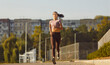 Young woman running at sunset in the city park. Jogging routine becomes a part of the outdoor workout and training, combining a active lifestyle with physical activities.