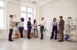 Full length photo of a group of diverse business people men and women chatting after meeting. Company employees or group of staff talking in modern office or conference room discussing work project.