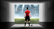 Portrait of a male football player standing with the ball in the stadium hallway before entering the pitch