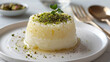 Exquisite presentation: aromatic persian rice pudding with crushed pistachios and mint, elegantly served on a white plate