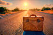 Vintage suitcase on a deserted road, adventure and travel concept.