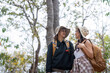 © Natee Meepian - Cheerful romantic lesbian couple traveler with backpack on their backs go hiking through the forest in the mountains in summer