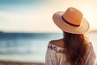 © lattesmile - A woman in a straw hat stands on a beach, vacation background, copy space