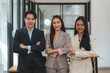 Young businessman and a beautiful Asian businesswoman stand with her arms crossed and pose for a beautiful team photo in the company.