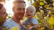 © kittikunfoto - Happy young family with baby enjoying a sunny day in the park, surrounded by lush greenery and warm sunlight.