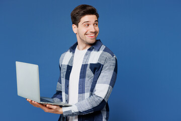 Poster - Side view young fun IT man wears shirt white t-shirt casual clothes hold use work on laptop pc computer browsing internet look aside on area isolated on plain blue cyan background. Lifestyle concept.