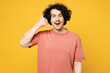 Young smiling happy amazed man he wear pink t-shirt casual clothes doing phone gesture like says call me back look camera isolated on plain yellow orange background studio portrait. Lifestyle concept.