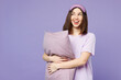 Young happy woman wears pyjamas jam sleep eye mask rest relax at home hold pillow look aside on copy space isolated on plain pastel light purple background studio portrait Good mood night nap concept