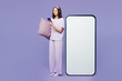 Full body young woman wear pyjamas jam sleep eye mask rest relax at home big huge blank screen area mobile cell phone use smartphone isolated on plain purple background. Good mood night nap concept.