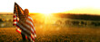 Girl with the American flag in a wheat field at sunset. 4th of July. Patriotic holiday, american day. Independence Day. 

