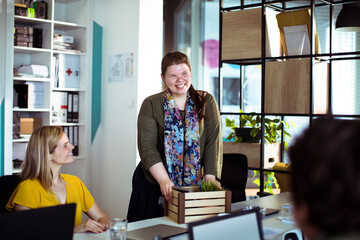Poster - Smiling woman with belongings interacting with coworker at new job office
