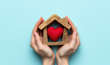 Fototapeta Zachód słońca - saving hands holding a wooden house with red heart inside