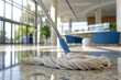 Close-up of a mop soaked in cleaning solution, ensuring thorough sanitation on the tiled floor of a corporate lobby