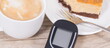 Glucometer for measuring sugar level, sweet cheesecake and cup of coffee with milk. Nutrition during diabetes