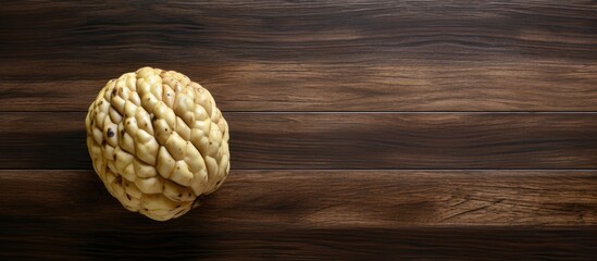 Poster - A ripe cherimoya fruit placed on a wooden table with a top down view The image has copy space and a horizontal aspect