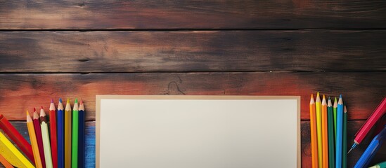 Aufkleber - Old wooden table with blank paper and colorful pencils ready for creative use in a copy space image