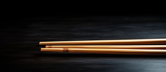 Poster - A copy space image of wooden chopsticks placed on a black table surface